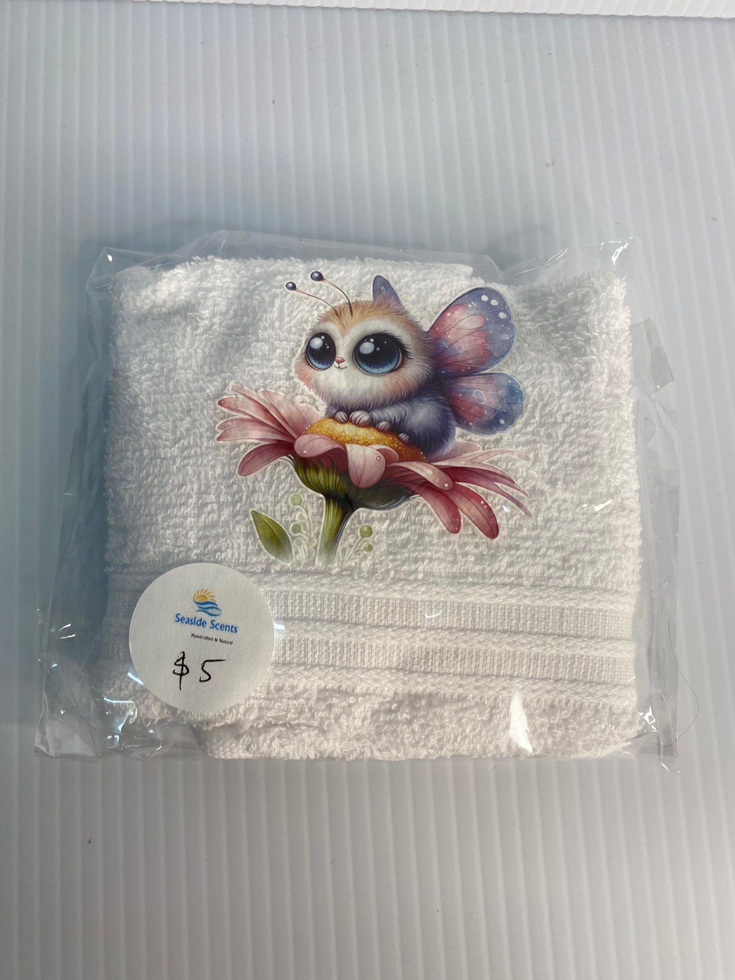 Baby Face Washer Furry Winged Baby sitting ontop of a pink flower on a White Washer